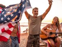 Man on beach with flag and woman with guitar